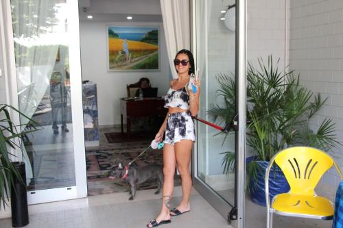 eine Frau in einem Kleid mit einem Hund an der Leine in der Unterkunft Martina's Hotel in Rimini