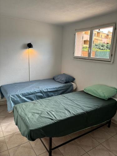 deux lits dans une chambre avec une fenêtre dans l'établissement Appartement proche de la mer, à Sainte-Marie-la-Mer