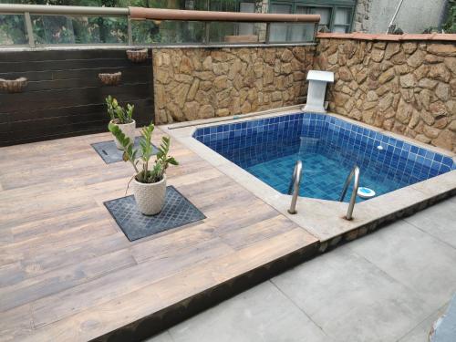a swimming pool with a wooden deck and a blue tiled at Casa Azul na Praia do Verão Vermelho in Cabo Frio