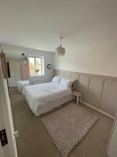 a white bedroom with two beds and a rug at Room in house close to Dover port in Temple Ewell