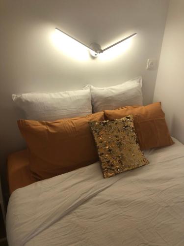 un letto con due cuscini e una luce sul muro di Chez Julien à 2 pas de La Défense a Puteaux