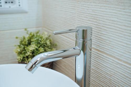 a bathroom sink with a faucet next to a plant at Next stop Ostia in Lido di Ostia