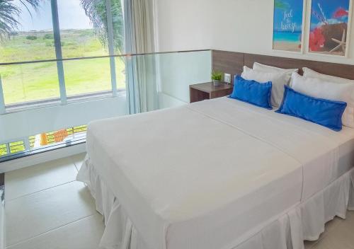 une chambre avec un grand lit blanc avec des oreillers bleus dans l'établissement Loft na praia em Resort 5 estrelas, à Trairi