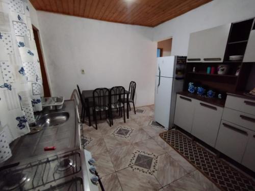 Una cocina con refrigerador y una mesa con sillas. en Casa Vista Verde, en Camanducaia