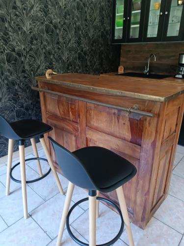 un bar en bois avec deux chaises à côté d'un évier dans l'établissement domaine des étangs du bois de l'abbaye, à Rejet-de-Beaulieu
