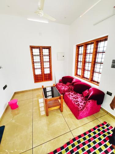 a living room with a red couch and windows at Tranquil Home in Trivandrum