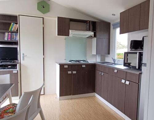 une petite cuisine avec des armoires marron et une fenêtre dans l'établissement "MHSweetHome" Piscine, 3 chambres 6 pers 32m2, à Houlgate