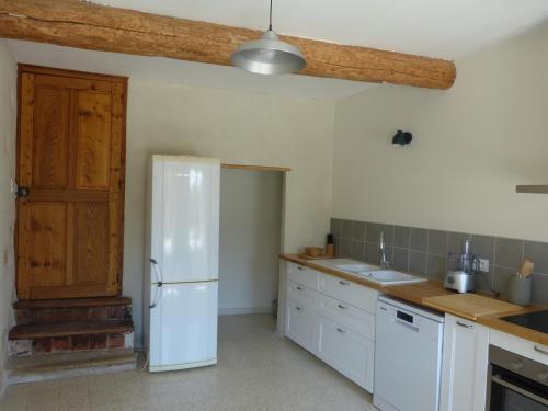 Il comprend une cuisine équipée d'un réfrigérateur blanc et une porte en bois. dans l'établissement Gite du domaine Saint-Marc, entre Ventoux et dentelles de Montmirail, à Caromb