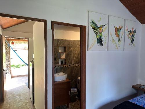 a bathroom with three paintings of birds on the wall at Casa Las Palmas Playa La Saladita in Zihuatanejo