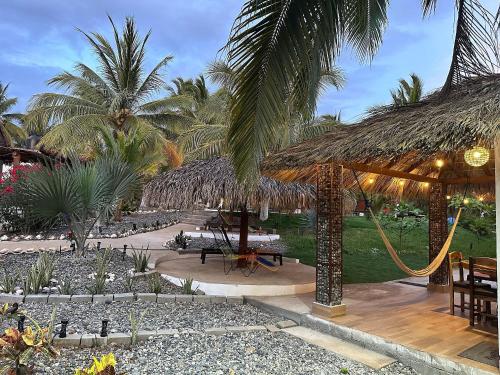 a resort with a hammock and tables and palm trees at Casa Las Palmas Playa La Saladita in Zihuatanejo