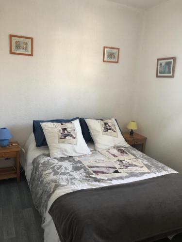 Ce lit se trouve dans un dortoir avec 2 tables et 2 photos sur le mur. dans l'établissement Appartement 2 pièces de plein pied au coeur du village a deux pas de la plage avec extérieur et parking prive, à Saint-Georges-de-Didonne
