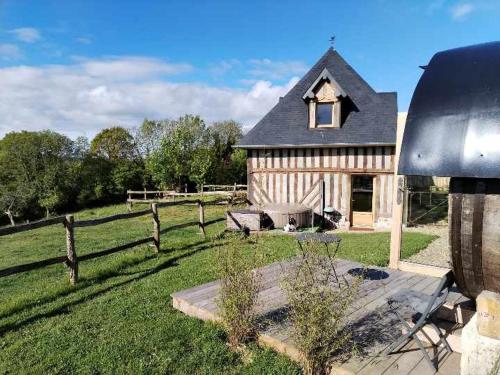 une grande maison avec une clôture et un champ dans l'établissement Tonneau normand insolite, à Le Mesnil-Germain