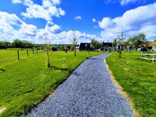 un chemin de gravier dans un champ avec des arbres et des maisons dans l'établissement Tonneau normand insolite, à Le Mesnil-Germain