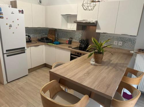 une cuisine avec une table en bois et un réfrigérateur blanc dans l'établissement Maison avec jardin et 2 places de parking, à Orly