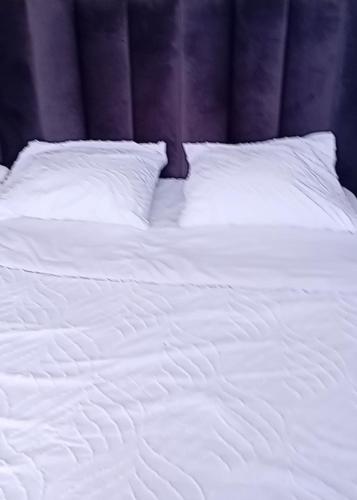 un lit blanc avec des draps et des oreillers blancs dans l'établissement Maison avec jardin et 2 places de parking, à Orly