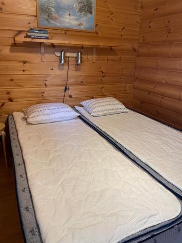 two beds in a room with wooden walls at Yllästölli 2 D, Äkäslompolo in Kolari