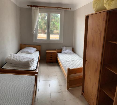 une petite chambre avec deux lits et une fenêtre dans l'établissement Appartement FRÉJUS 300m de la PLAGE 3 Chambres 7 lits, à Fréjus