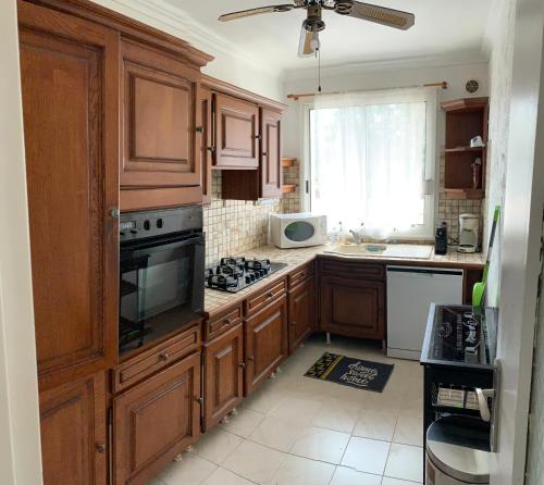 une cuisine avec des armoires en bois et un four à plaques de cuisson dans l'établissement Appartement FRÉJUS 300m de la PLAGE 3 Chambres 7 lits, à Fréjus