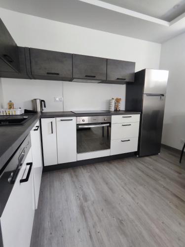 une cuisine avec des armoires blanches et des appareils en acier inoxydable dans l'établissement Les orangers, à Ravilloles