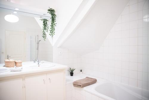 une salle de bain avec deux lavabos, une baignoire et un miroir dans l'établissement La Bastide, à Carcassonne
