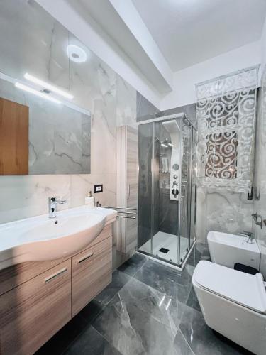 a bathroom with a sink and a shower and a toilet at La Bella Sicilia Suite in Floridia