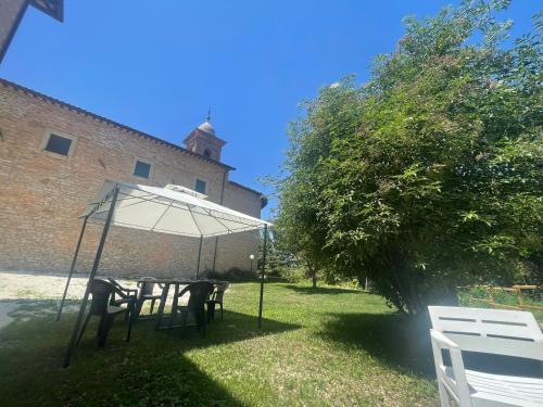 a table with an umbrella in the yard of a building at Antica Residenza Colle in Nocera Umbra
