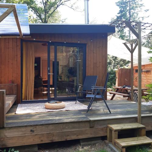 a tiny house with a porch and a chair on a deck at Natuurhuisje Govinda in Laag-Soeren