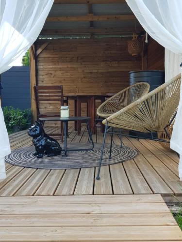 un chien noir assis sur une terrasse avec une table et des chaises dans l'établissement L'échappée de Sologne -chez l'habitant-, à Lamotte-Beuvron
