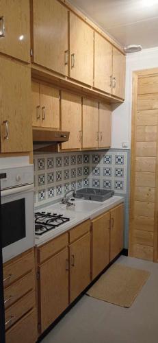 une cuisine avec des armoires en bois et un four à plaques de cuisson dans l'établissement Au Domaine de L'étang, à Saint-Priest-sous-Aixe