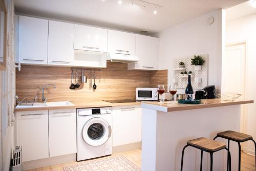une cuisine avec des armoires blanches et une laveuse et une sécheuse dans l'établissement 101 Cour de la Bastide, à Carcassonne