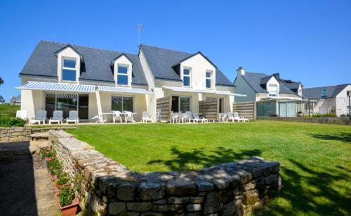 une grande maison avec un mur de pierre devant elle dans l'établissement Le Clos de La Plage, à Erdeven