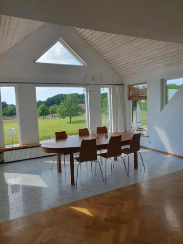 a dining room table with chairs and a large window at Gamla macken Utsikten in Hjärnarp