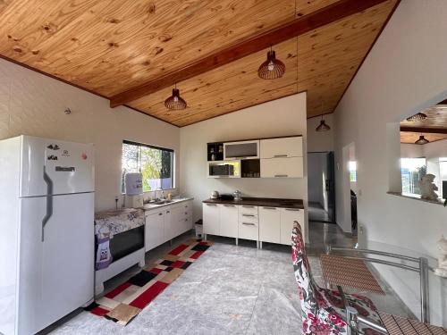 a kitchen with white appliances and a wooden ceiling at Casa Pôr do Sol in Baependi
