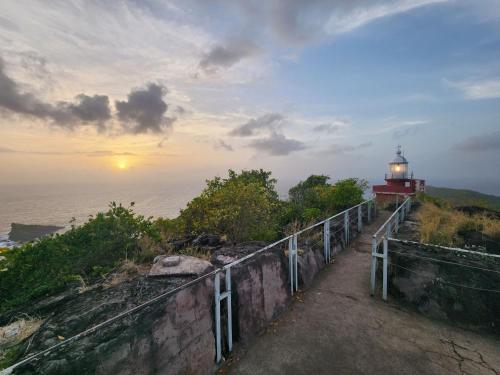 a lighthouse on top of a hill with the ocean at Kozy Kaz - Les pieds dans l eau in La Trinité