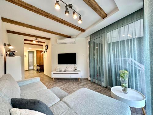 a living room with a couch and a tv at LAKE MOMENTS - Ruby Garden Apartment in Balatonszemes