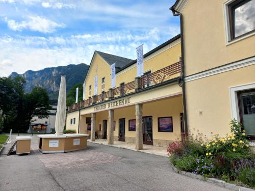 a hotel exterior with a building and mountains in the background at Ferienwohnung Detox in Payerbach