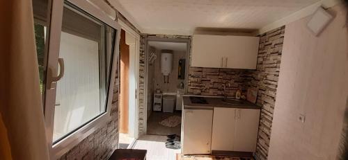 a small kitchen with white cabinets and a brick wall at Smještaj na selu,porodica Gvozdenac in Šipovo