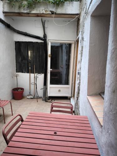 une table rouge et deux chaises sur la terrasse dans l'établissement Cosy studio, à Avignon