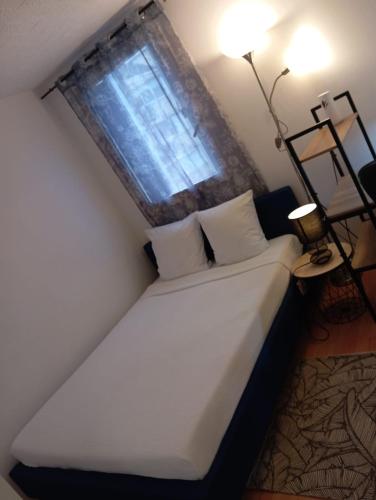 a white bed in a room with a window at Noxio voyages in Evry-Courcouronnes