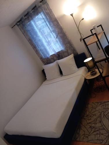 a bedroom with a white bed with a window at Noxio voyages in Evry-Courcouronnes