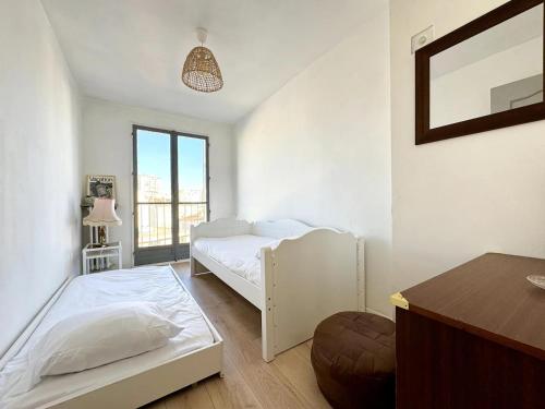- une chambre blanche avec 2 lits et une table dans l'établissement T4 exceptionnel vue sur mer à 5 min à pied du métro, à Marseille