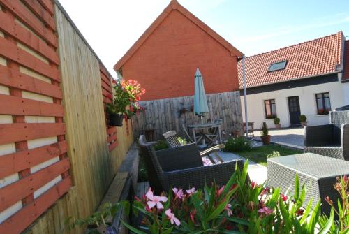 une cour arrière avec une clôture, des chaises et un parasol dans l'établissement Gîte La Laiterie, à Wanquetin