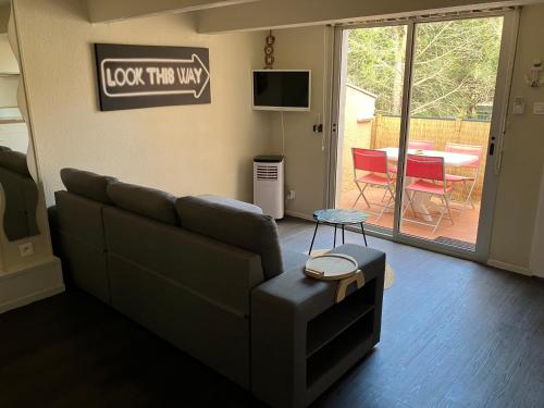un salon avec un canapé et une table dans l'établissement Appartement vue Piscine sous les Pins, au Cap d'Agde