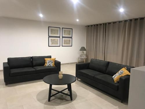 a living room with two black couches and a table at Gîte des 6 tilleuls in Bomy