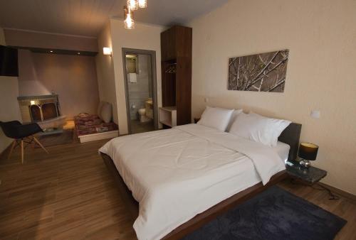 a bedroom with a large white bed and a fireplace at Livadi Suites in Arachova
