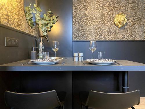 - une table avec deux assiettes et des verres dans l'établissement La folie sauvage - Balnéo & haut de gamme, à Saint-Nazaire