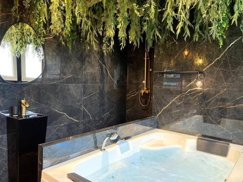 La salle de bains est pourvue d'une baignoire et d'un lavabo. dans l'établissement La folie sauvage - Balnéo & haut de gamme, à Saint-Nazaire