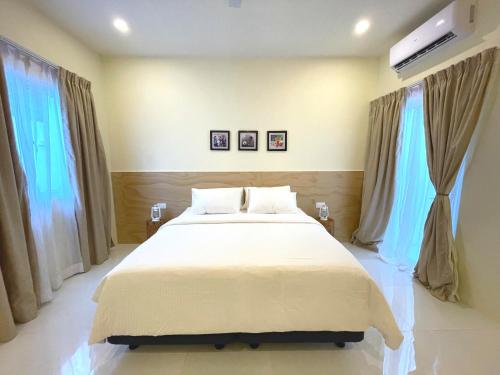 a bedroom with a large bed and two windows at Stay Kora in Thinadhoo