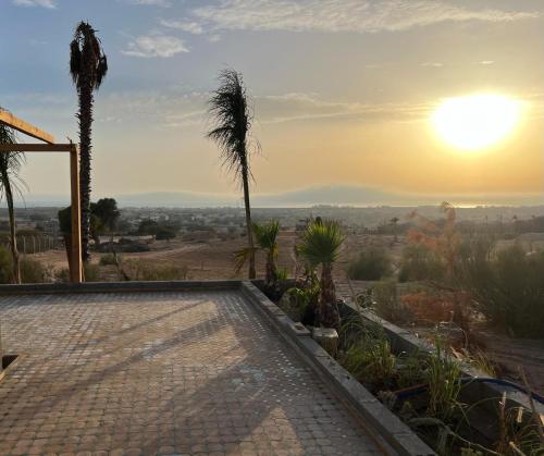 a swimming pool with a palm tree and the sunset at Romantic Best View - Saïss Bay Estate - Coco Green in Sidi Kaouki