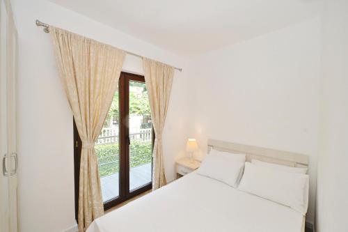 a bedroom with a white bed and a window at Pearl Shell Apartments in Kotor